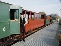 one end of the brakevan, with the guard in smart uniform standing on the platform
