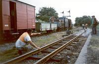 varied freight train; workmen in foreground