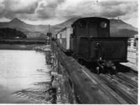 locomotive runs tender first across old river bridge