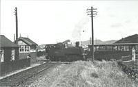 train crossing a single-track standard gauge railway; signalbox; wooden building