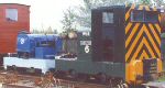 cabless blue Cnicht surrounded a by green Simplex and a bauxite orange brake van